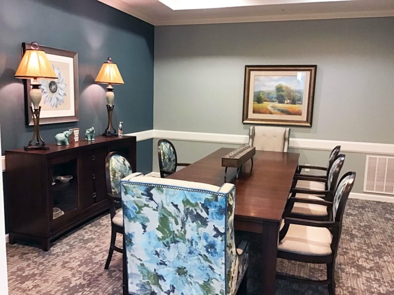 A well-decorated conference room featuring a long wooden table, upholstered chairs, and artwork on the walls.