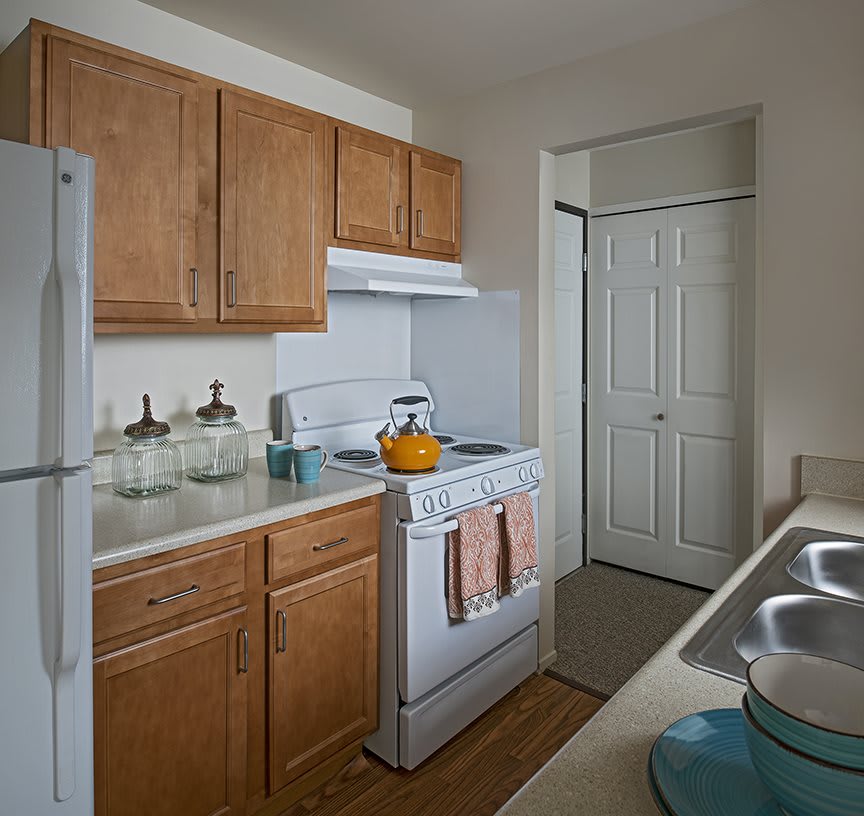A compact kitchen with wooden cabinets, stove, and refrigerator.