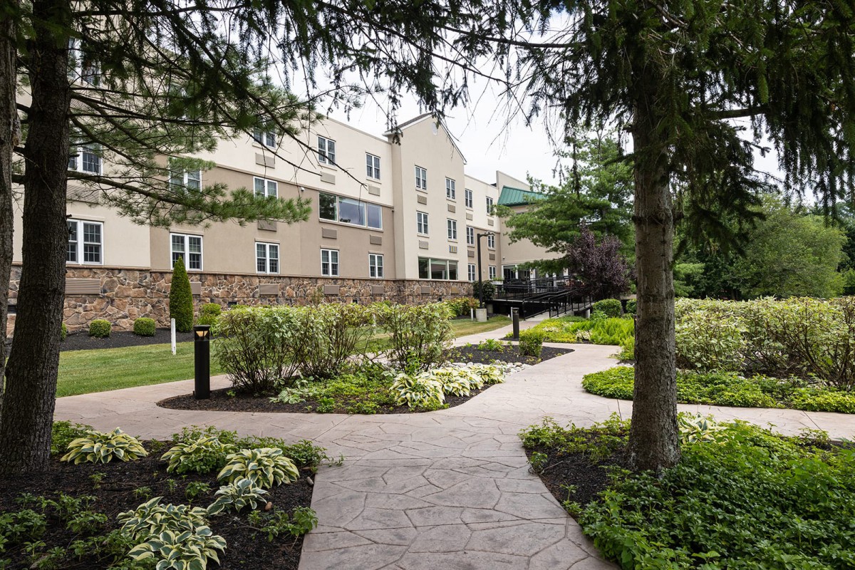 A beautifully landscaped garden path leading to a modern building surrounded by lush greenery.
