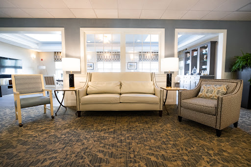 A cozy living room featuring a modern sofa and comfortable armchair, complemented by stylish lamps and a decorative carpet.