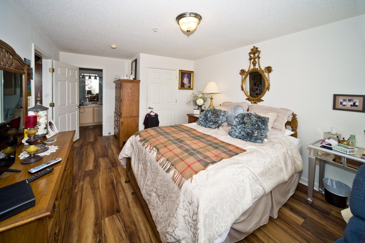 A cozy bedroom featuring a double bed with plaid bedding, wooden furniture, and elegant decor.