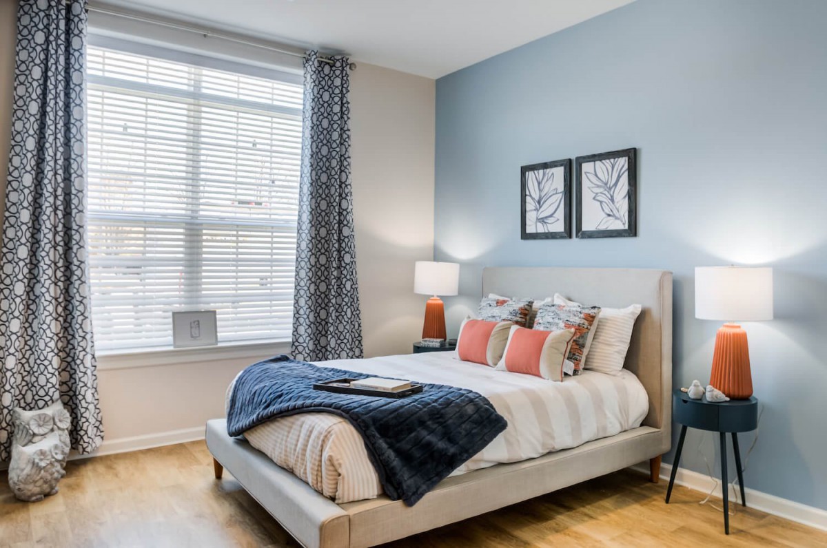 A modern bedroom with blue accents, decorative pillows, and framed artwork, creating a cozy and stylish atmosphere.