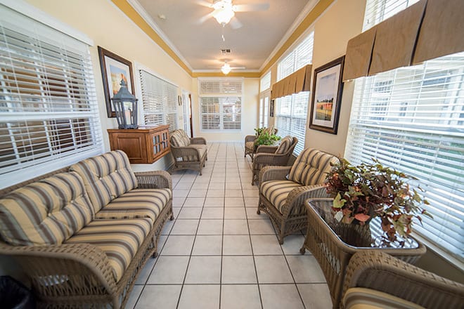 A bright sunroom featuring wicker furniture and large windows.