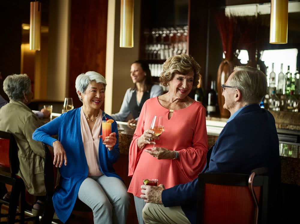 A group of people enjoying drinks and conversation at a bar.