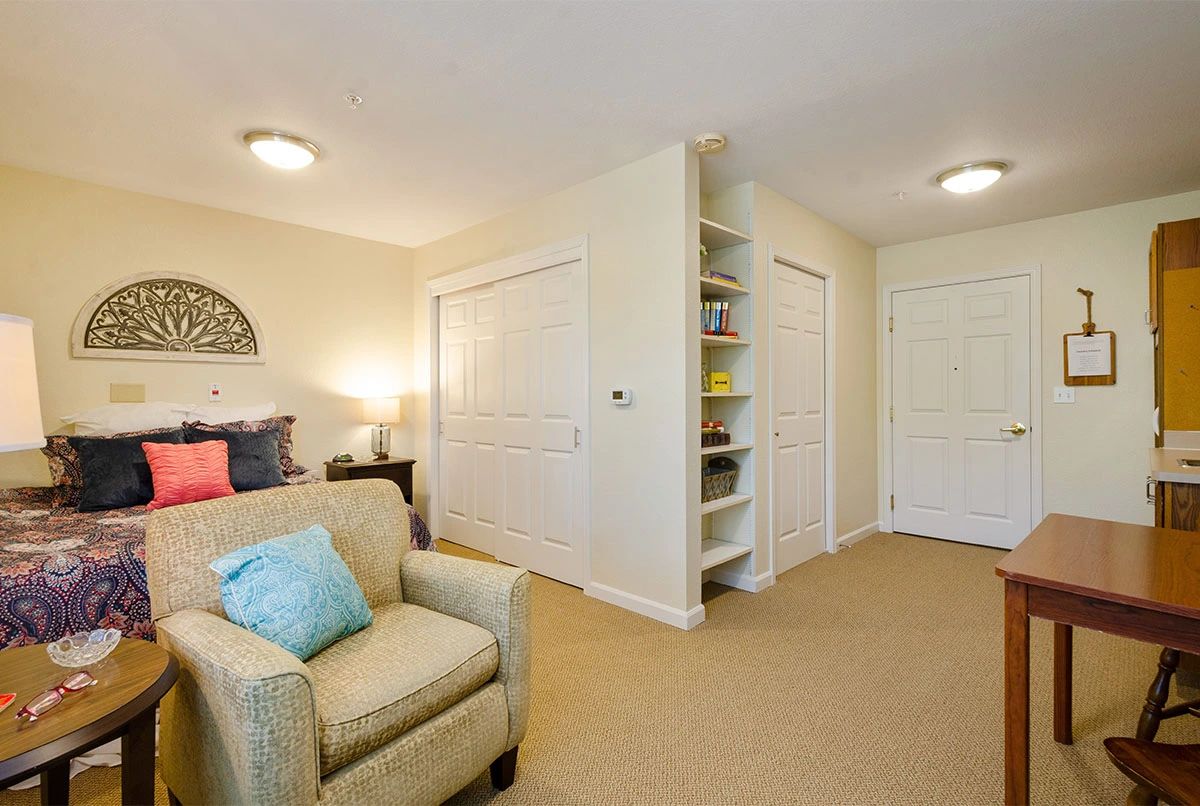 A cozy living room with a comfortable armchair, built-in shelves, and soft lighting.