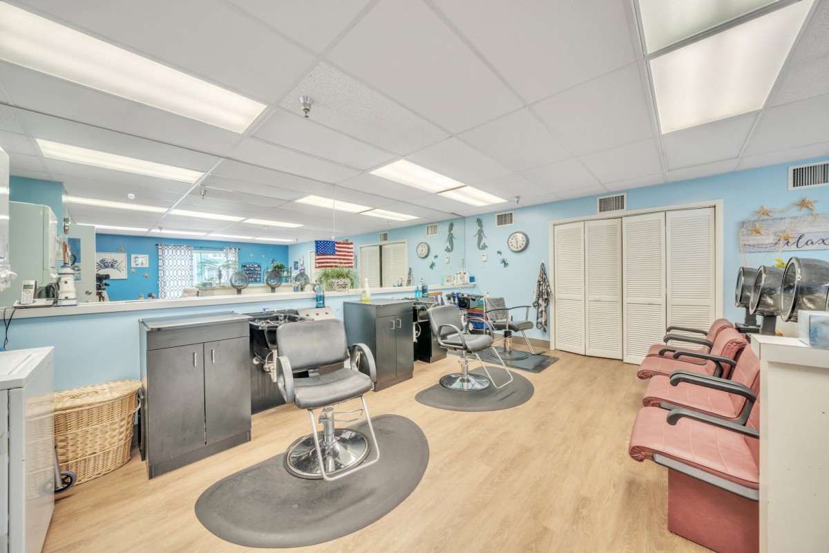 An empty barbershop with multiple barber chairs and mirrors lining the walls.