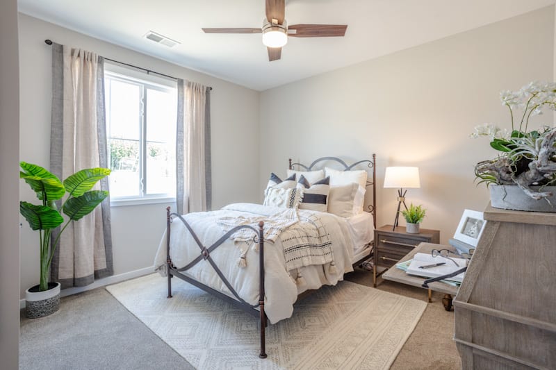 A modern bedroom featuring a neatly made bed, bedside tables with lamps, and a large window letting in natural light.