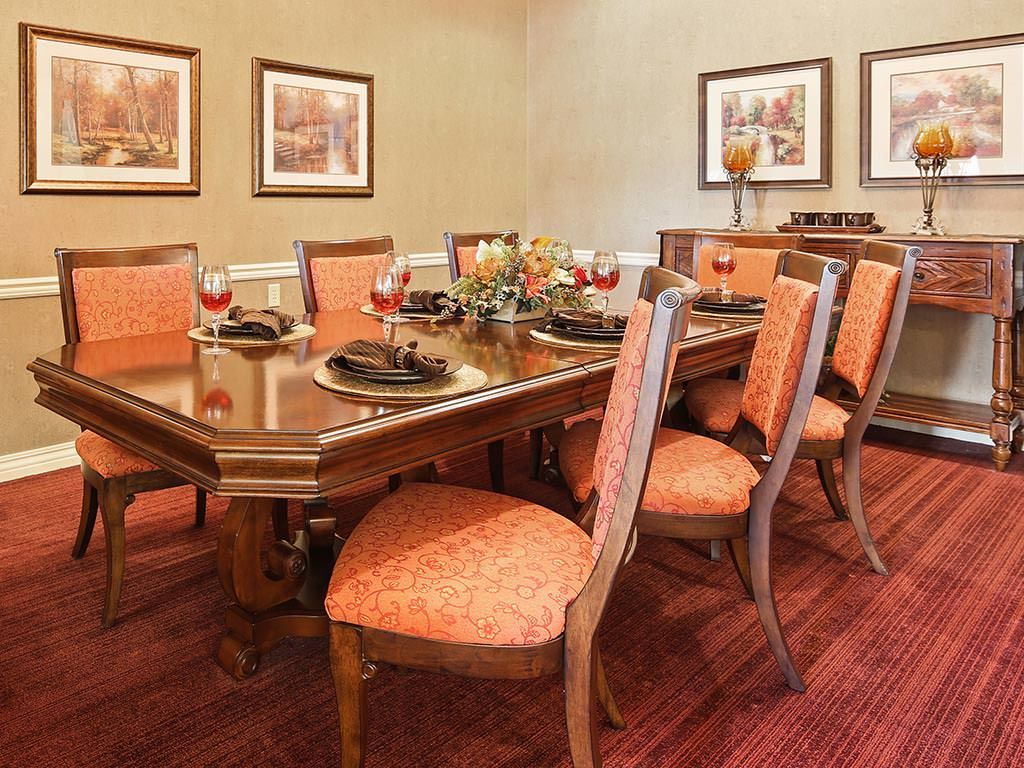 A beautifully arranged dining room with a wooden table and upholstered chairs, adorned with elegant tableware and surrounded by artwork.
