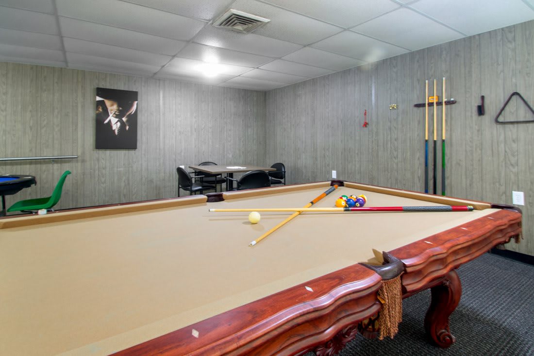 A cozy recreation room featuring a well-maintained pool table with cue sticks and balls ready for a game.