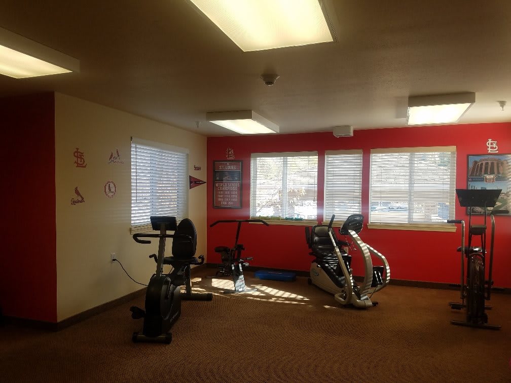 A small gym room with exercise equipment and large windows.