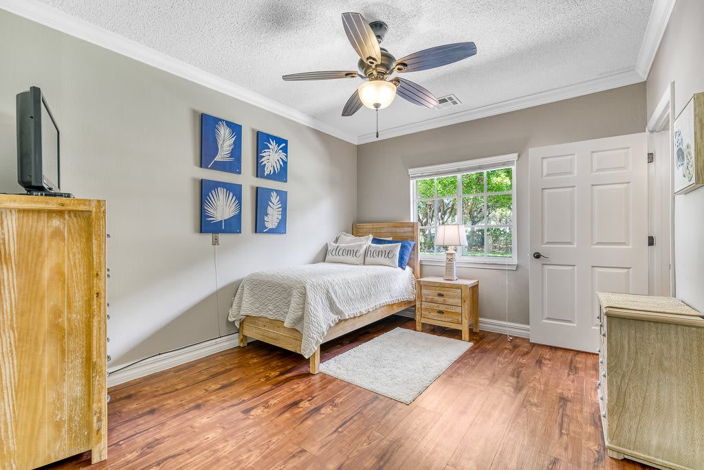 A cozy bedroom with a single bed, ceiling fan, and modern decor.