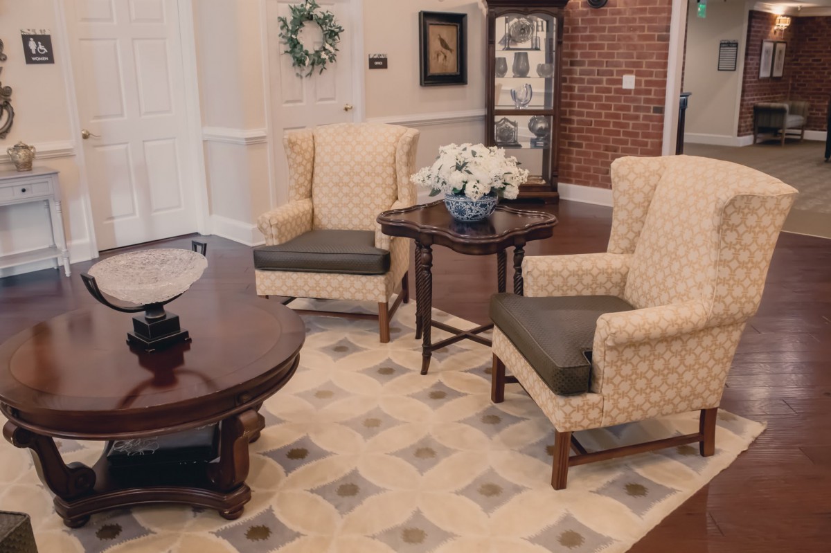 A cozy living room with armchairs and coffee tables, featuring elegant decor and a patterned rug.