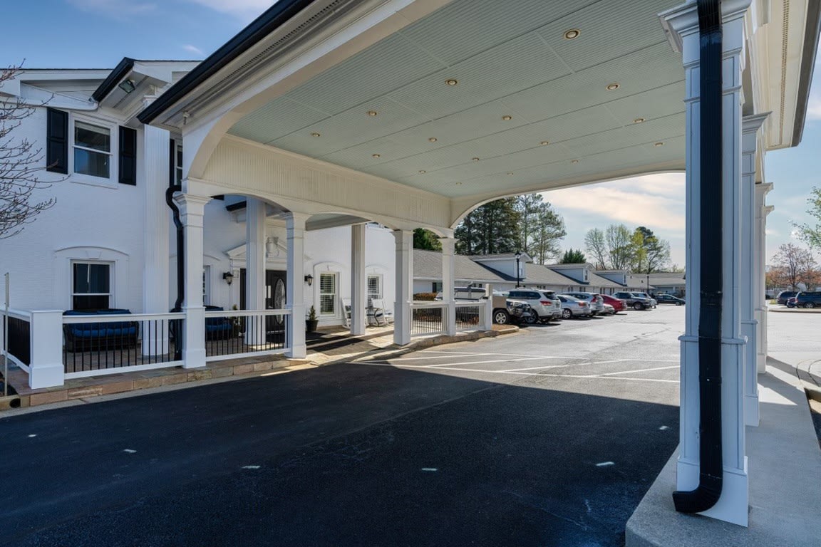 A building with a covered entrance and an adjacent parking lot.