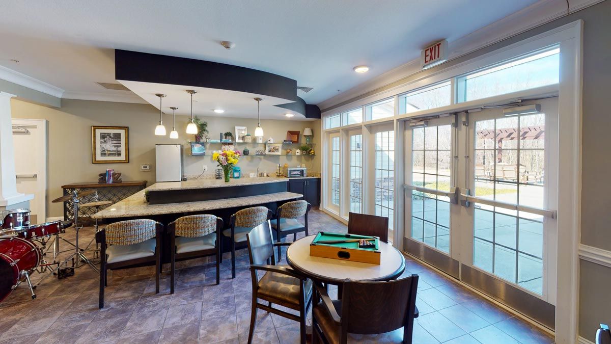 A modern kitchen and dining area with a bar counter, stylish chairs, and large windows letting in natural light.