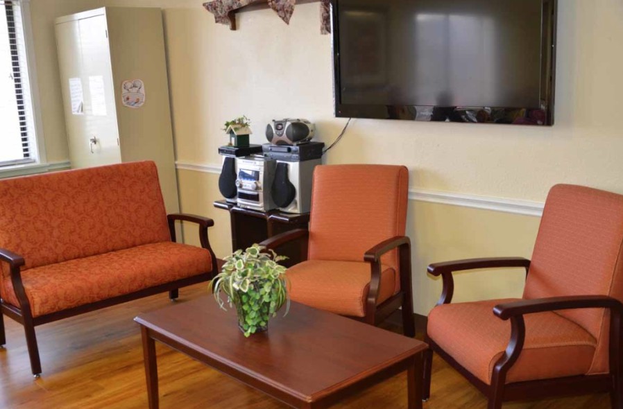 A cozy living room with comfortable chairs, a wooden table, a television, and a stereo system.