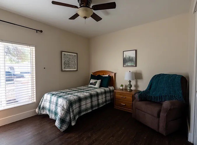 A cozy bedroom with a single bed, nightstand, and chair.