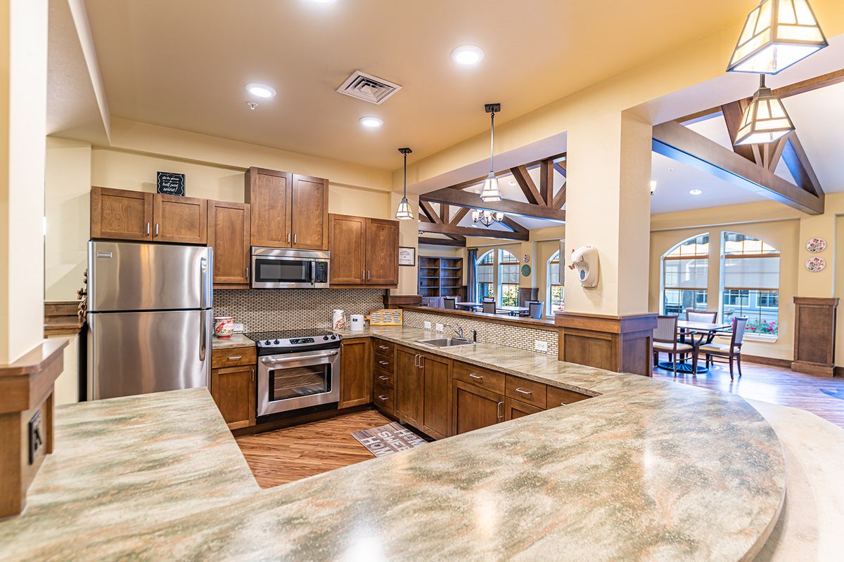 A modern kitchen with wood cabinets, stainless steel appliances, and granite countertops in an open concept layout.