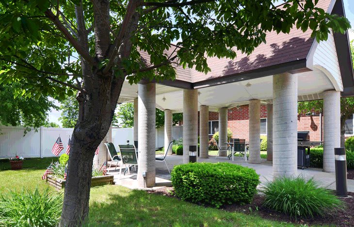 A shaded patio area with seating and garden greenery.