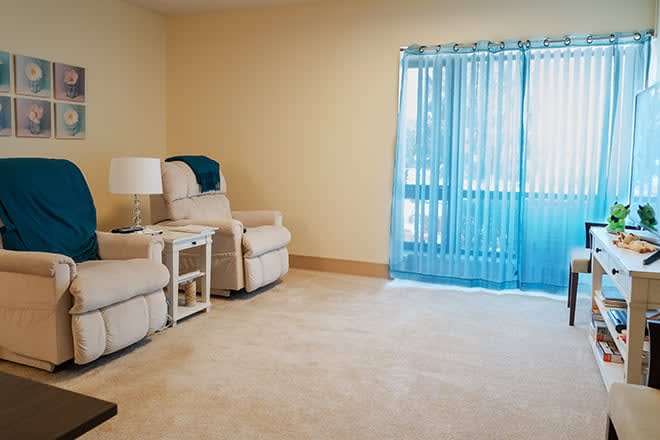 Cozy living room with recliners, a side table, and bright blue curtains.