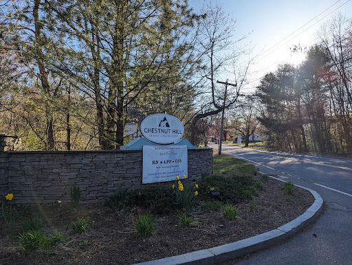 Entrance sign surrounded by trees, leading to a residential area.