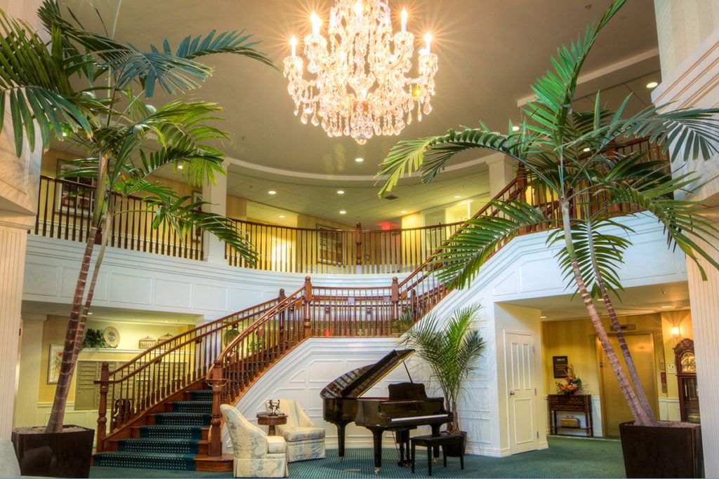 A luxurious interior featuring a grand staircase, elegant chandelier, and a piano.