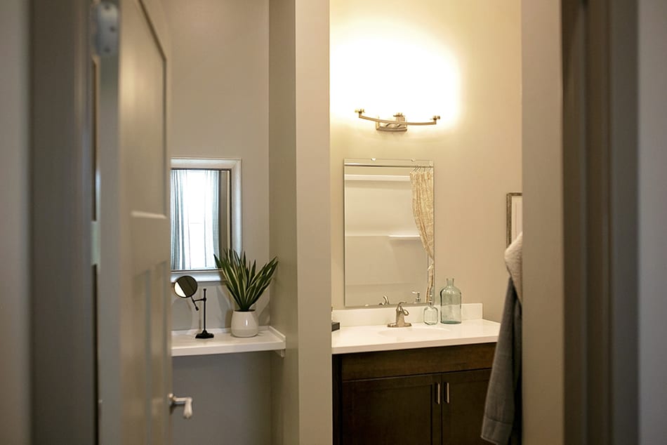 A modern bathroom featuring a mirror, sink, and decorative plant under soft lighting.