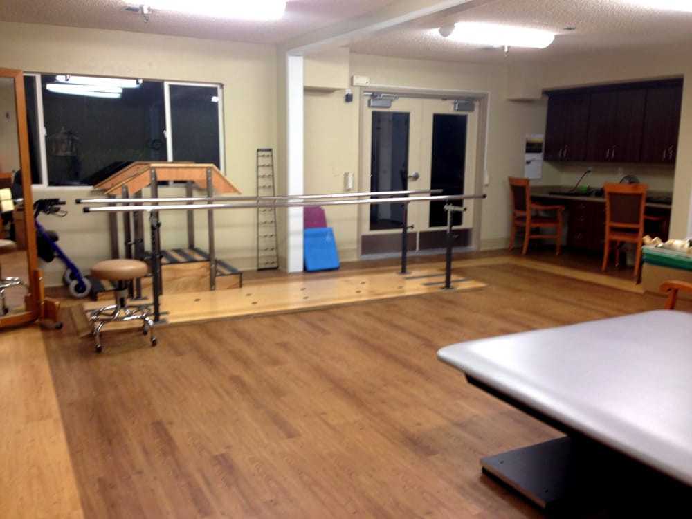 A rehabilitation room equipped with parallel bars and exercise equipment for physical therapy.