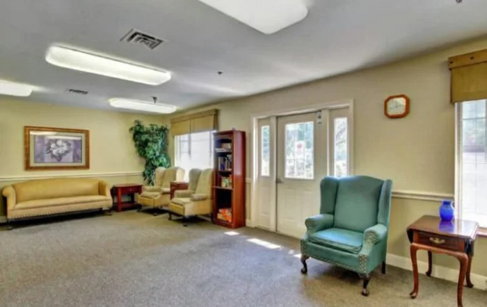 A warmly lit waiting room with several armchairs and a bookshelf against the wall.