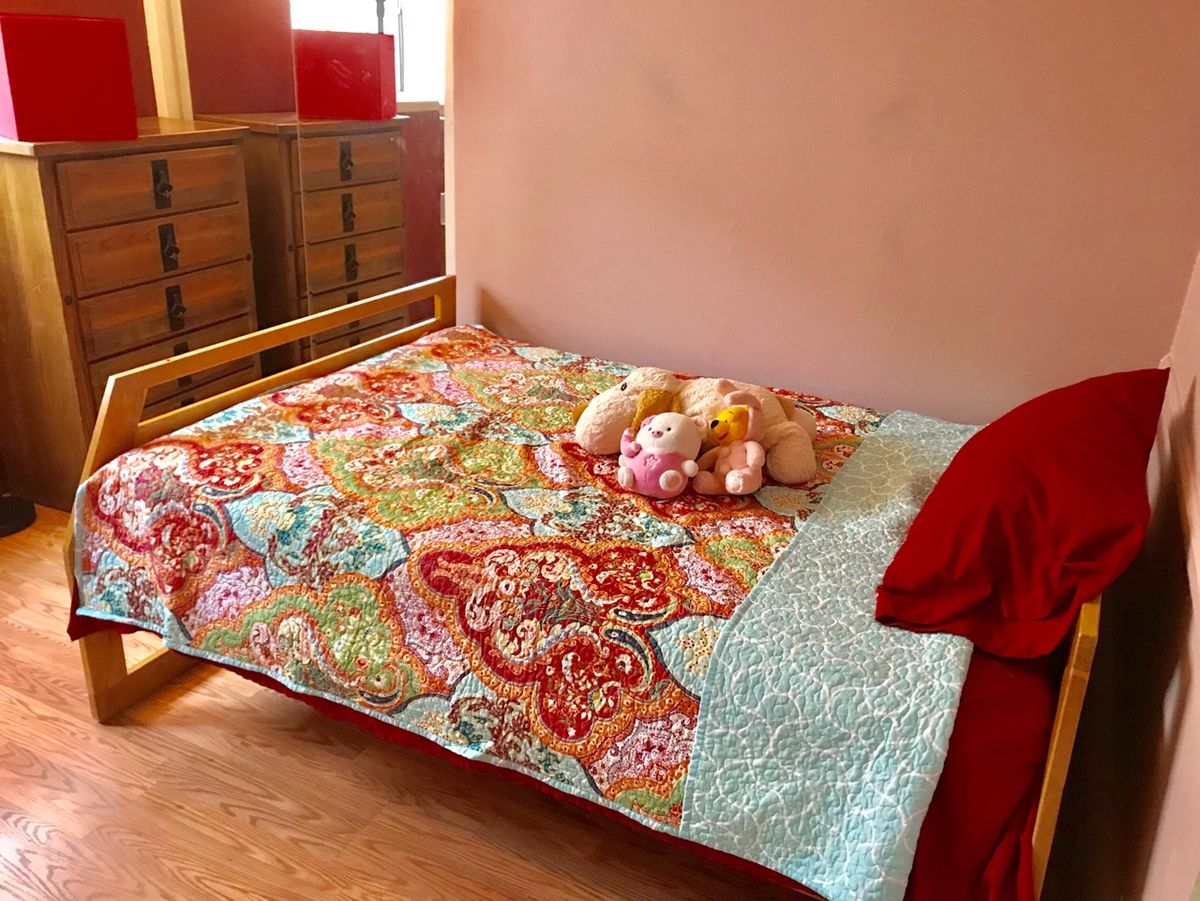 A cozy bedroom with a colorful quilt on the bed and teddy bears placed on top.