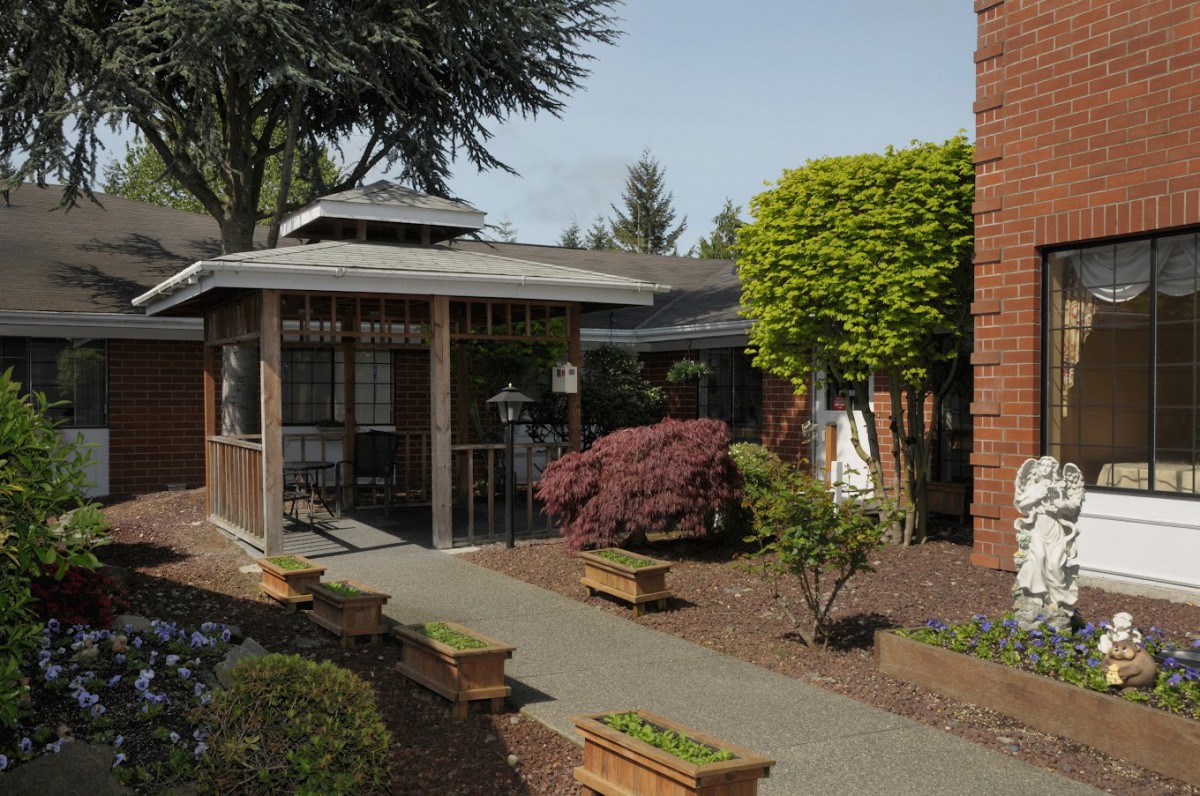 A well-maintained garden with a gazebo and a paved pathway surrounded by lush greenery.