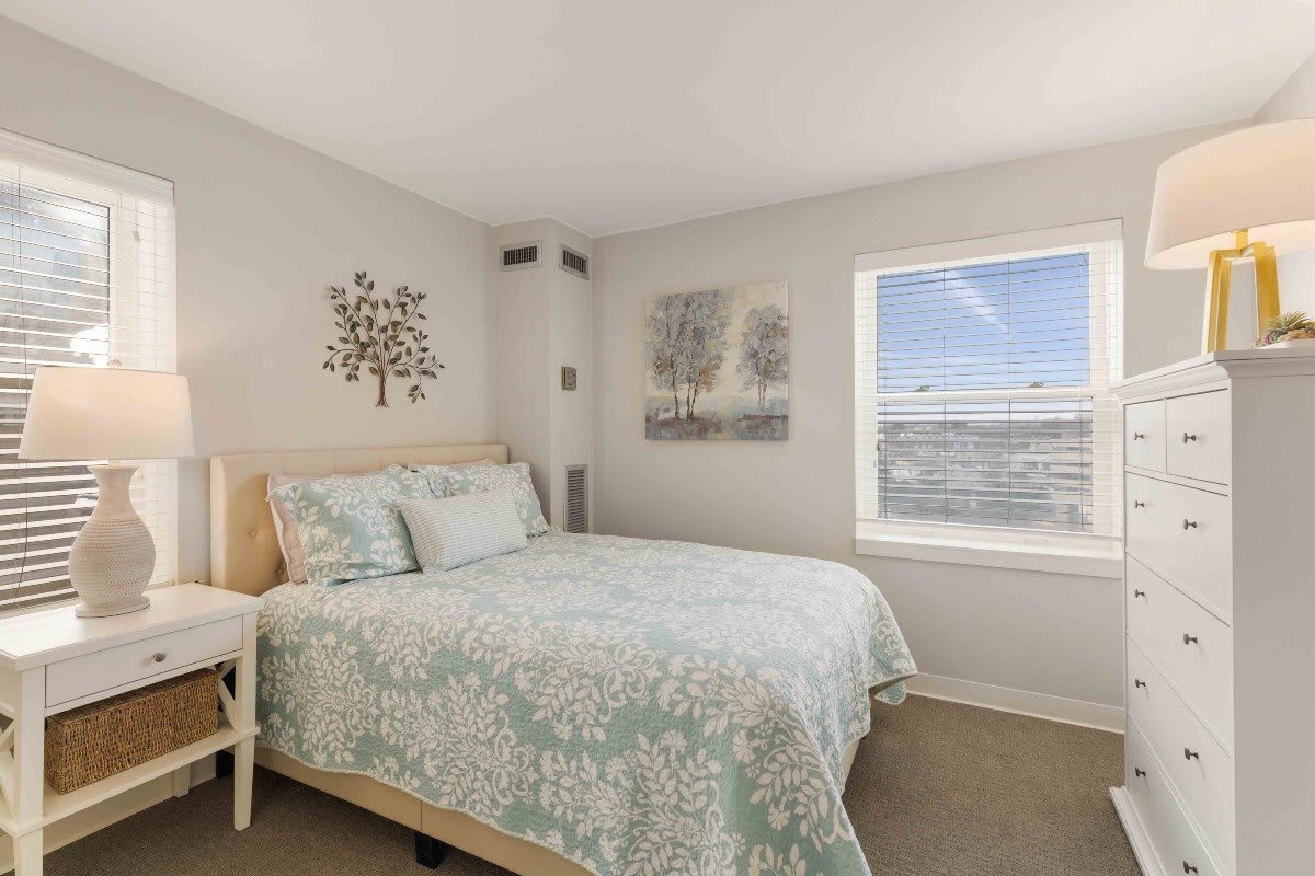 A cozy bedroom with a neatly made bed, soft lighting, and decorative wall art.
