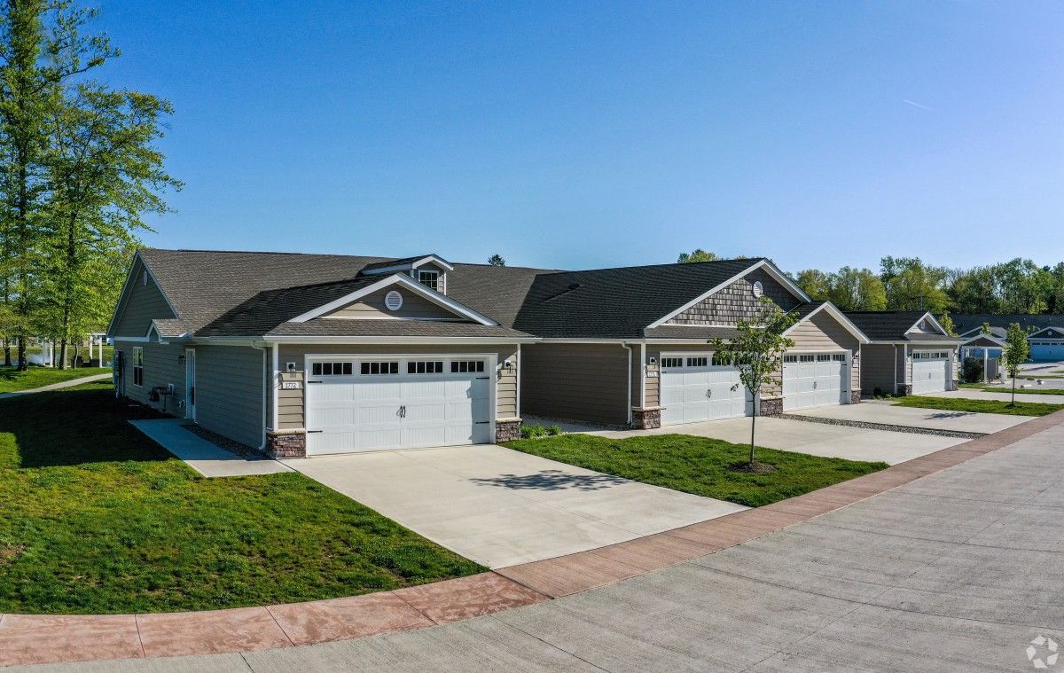 A row of suburban houses with driveways and garages on a clear day.
