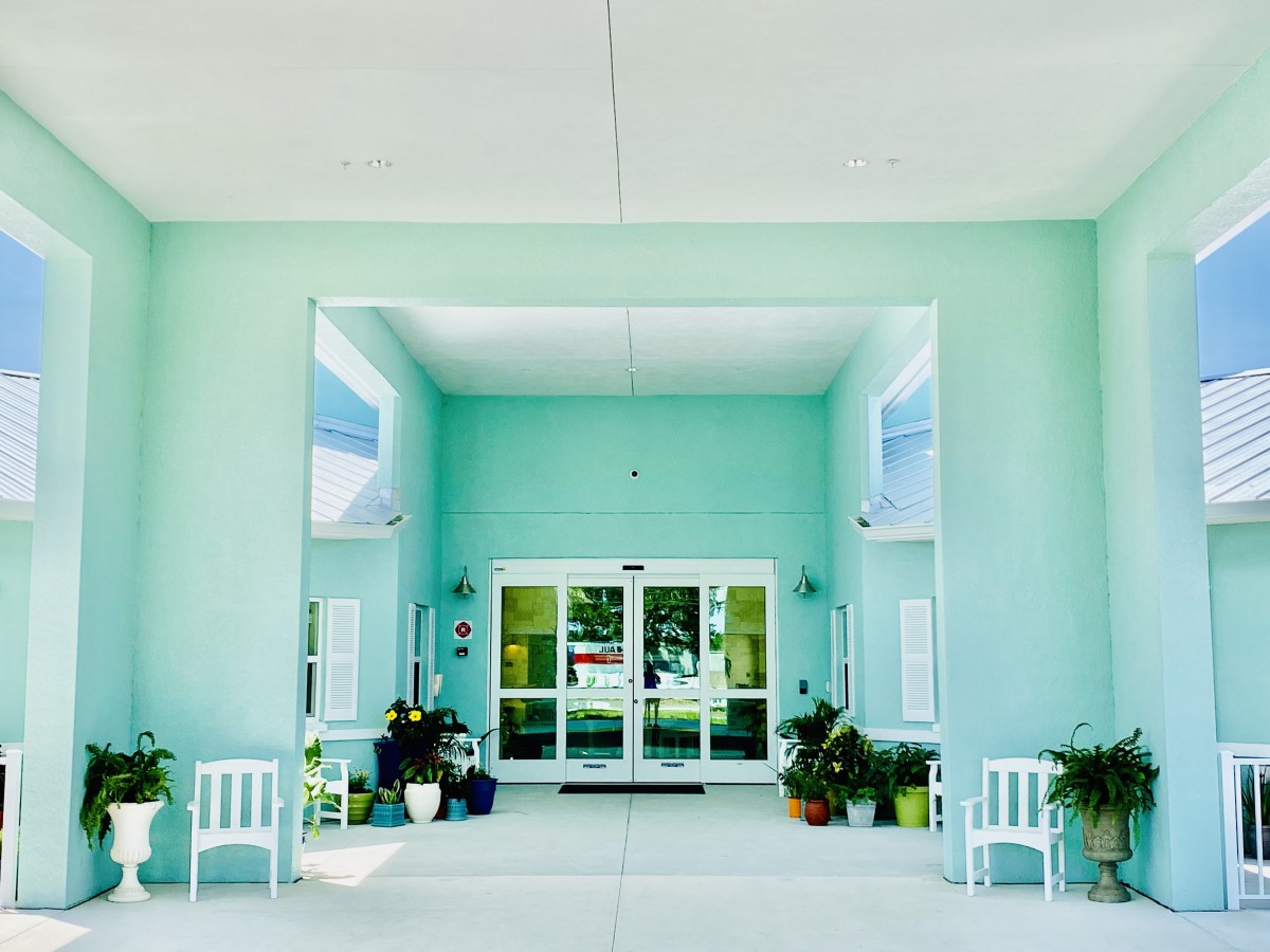 A symmetrical building entrance with plants and chairs.