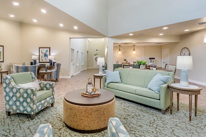 A cozy and well-lit living room with green sofas and a round coffee table.