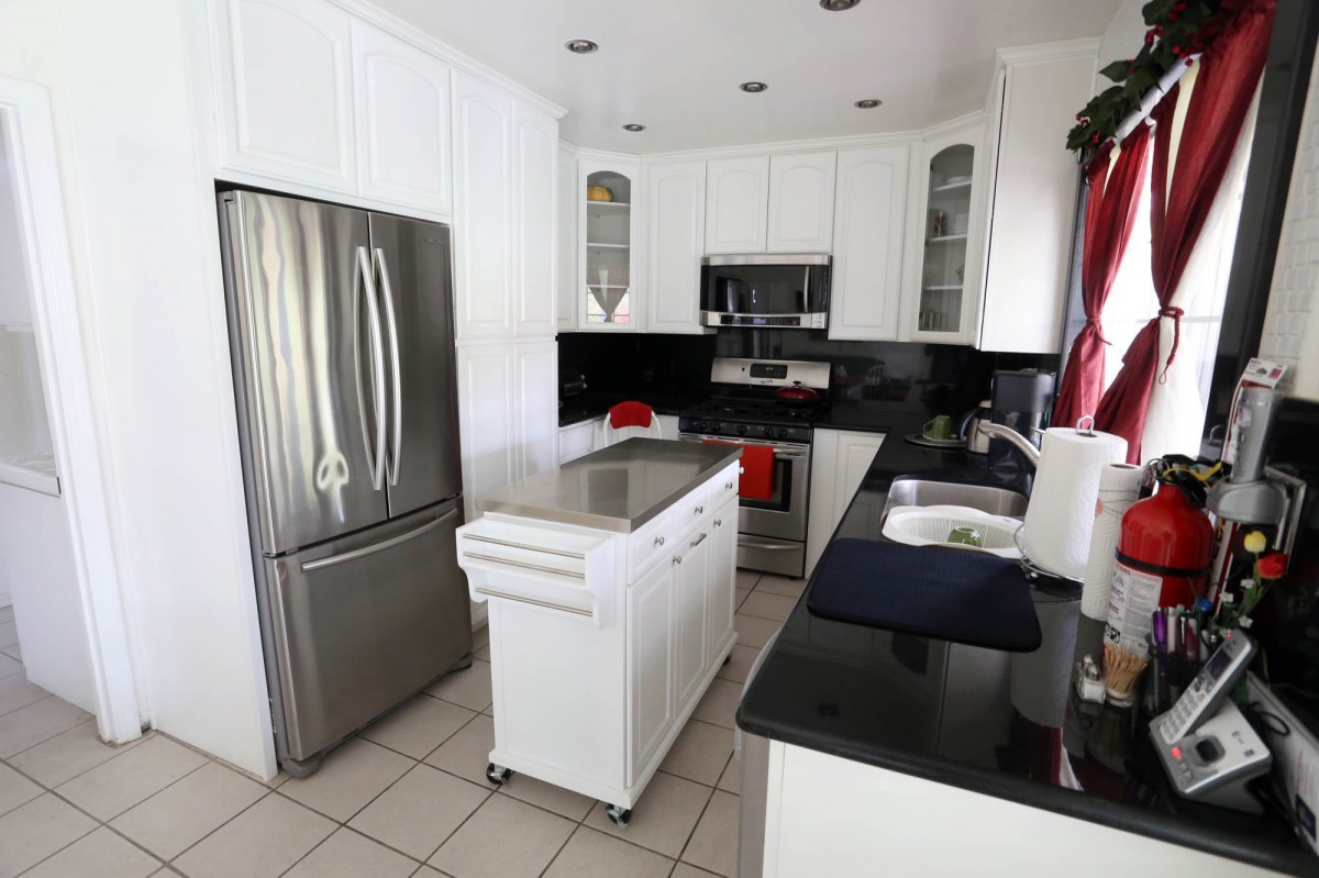 A modern kitchen featuring white cabinets, black countertops, and stainless steel appliances.