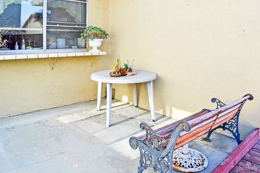 A cozy outdoor patio with a white round table and a decorative bench.