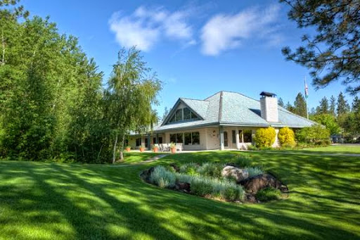 A beautiful residential house surrounded by lush greenery under a clear blue sky.