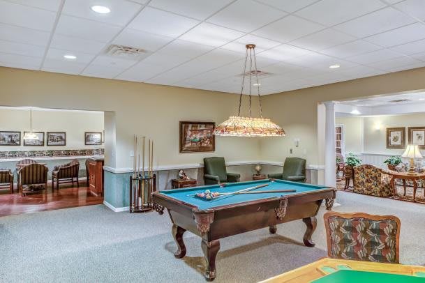 A well-lit billiards room with a pool table and comfortable seating.