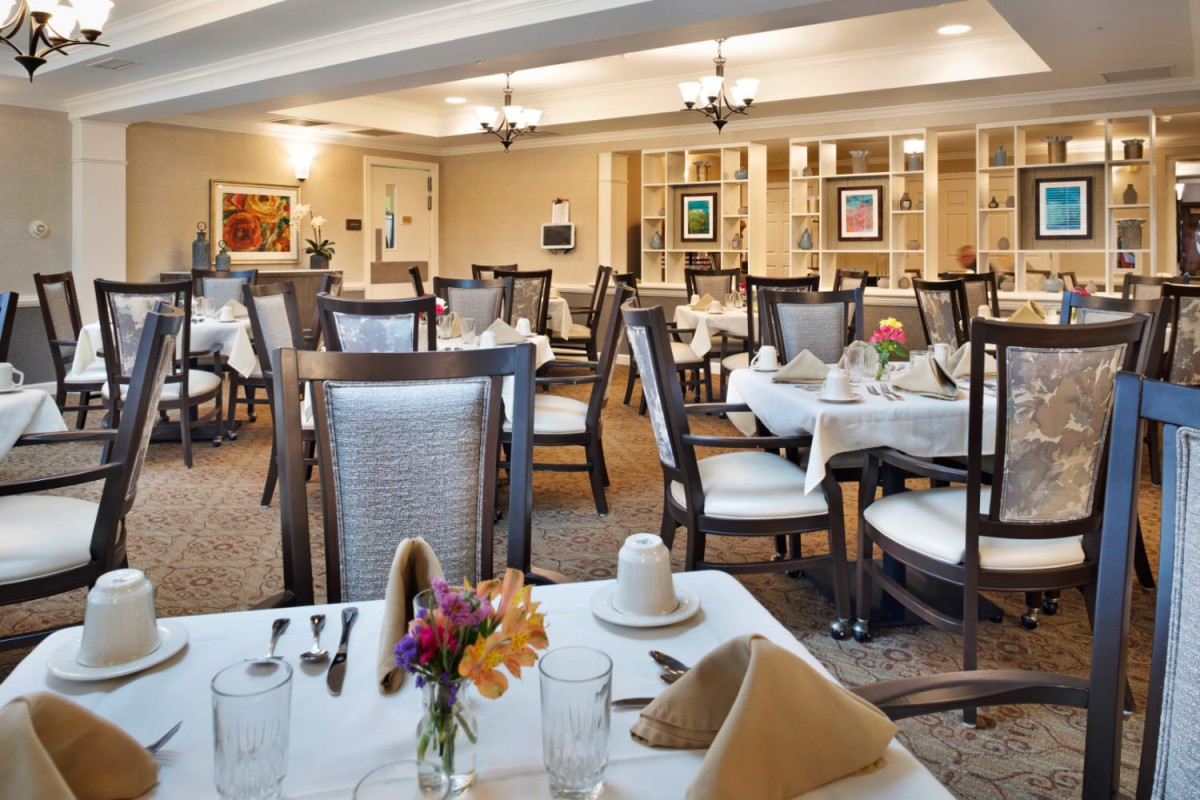 An elegant dining room with neatly arranged tables and chairs, adorned with flowers and place settings.