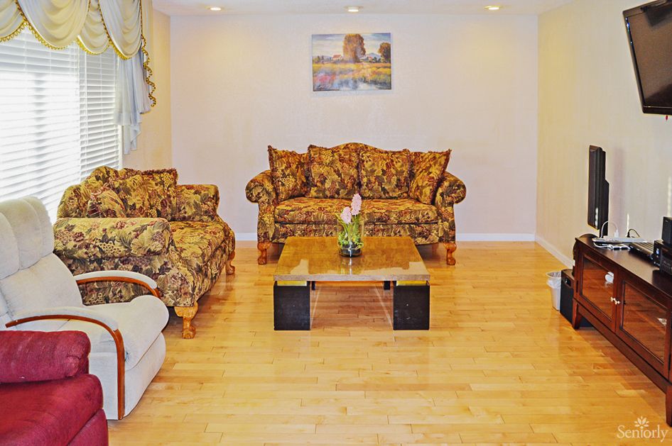 A cozy living room with patterned sofas, a glass coffee table, and wooden flooring.