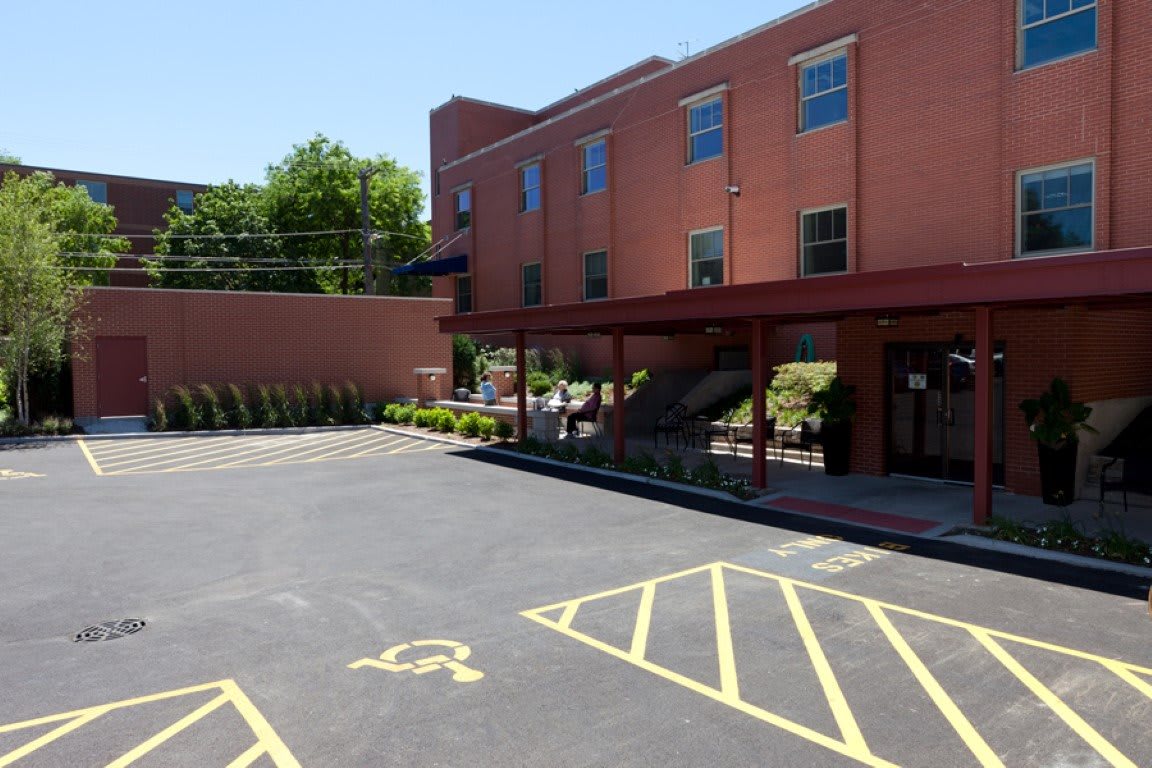 A paved parking lot with designated handicap parking spaces in front of a red brick building.