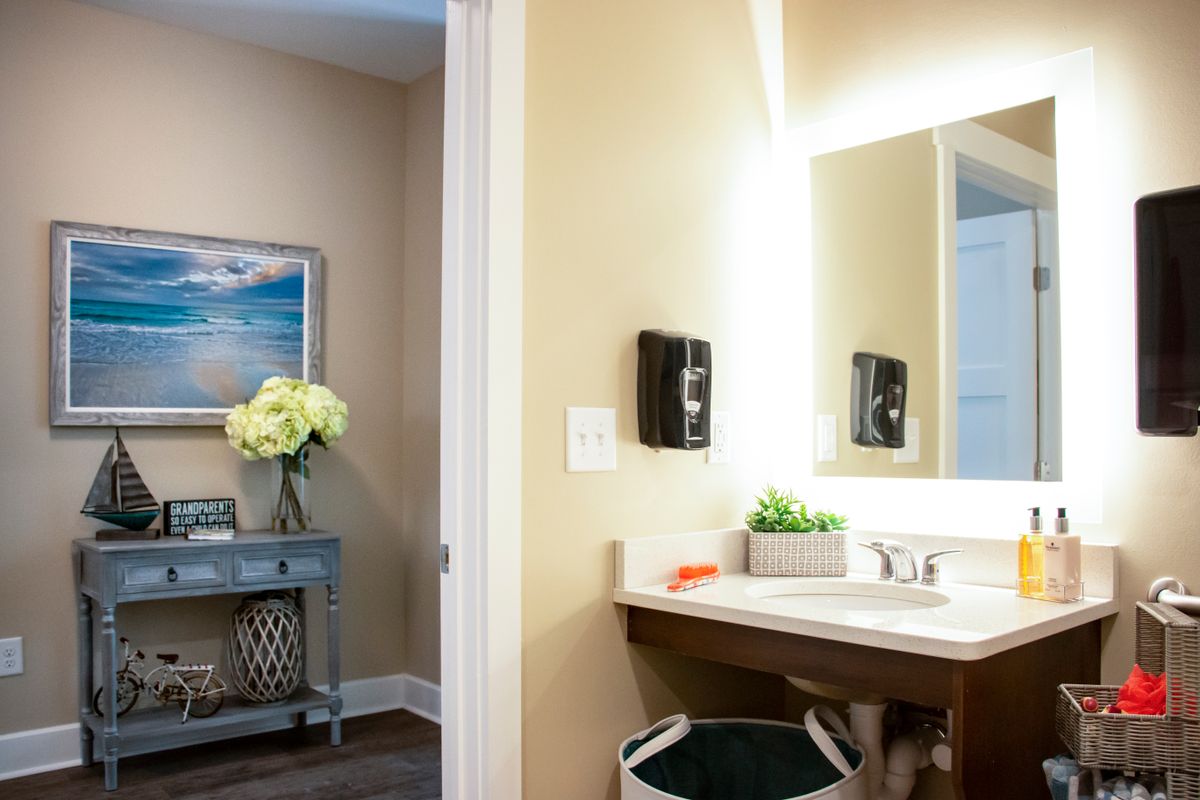 A well-lit bathroom featuring a modern sink, decorative flowers, and wall art.