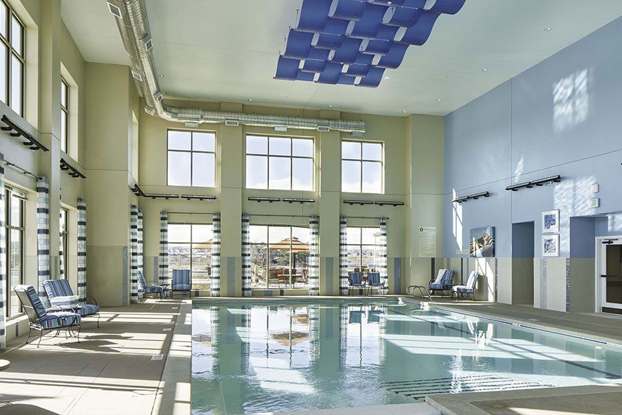 A modern indoor swimming pool with ample natural light and stylish decor.