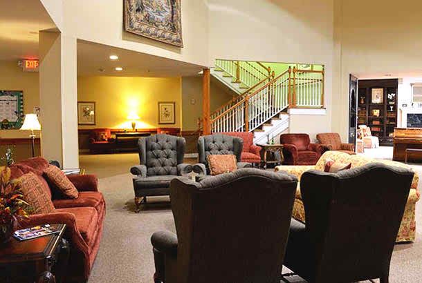 A cozy lobby with comfortable seating and a staircase in the background.