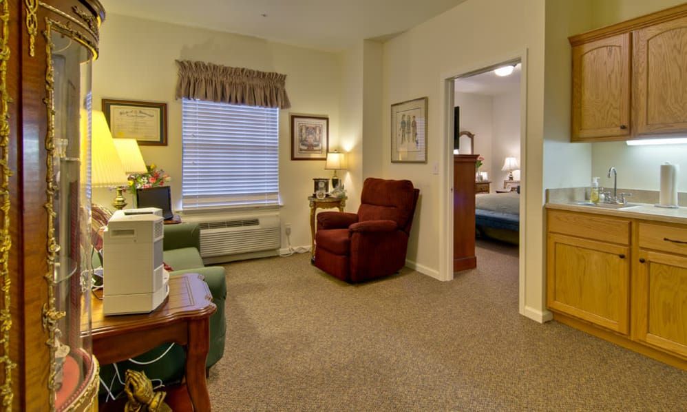 A cozy living room with an armchair, television, and a window adorned with curtains.