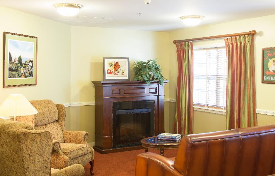 A cozy living room with a fireplace, armchair, and window with curtains.
