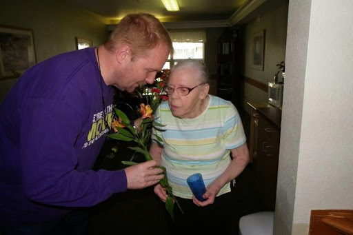 A moment of connection as a caregiver presents flowers to an elderly individual.