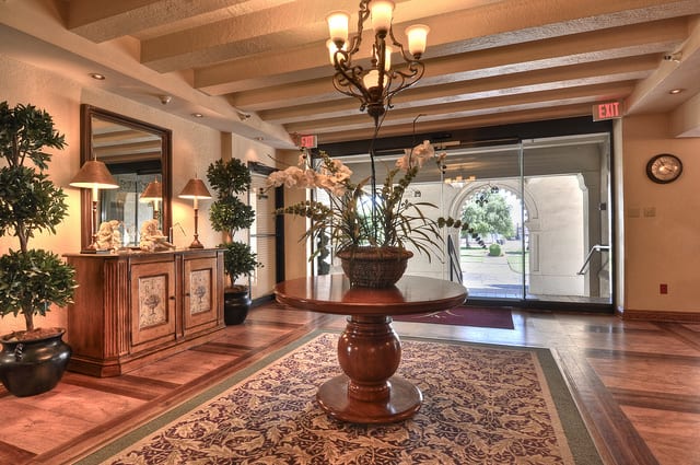 Elegant lobby with a central floral arrangement on a wooden table and a chandelier overhead.