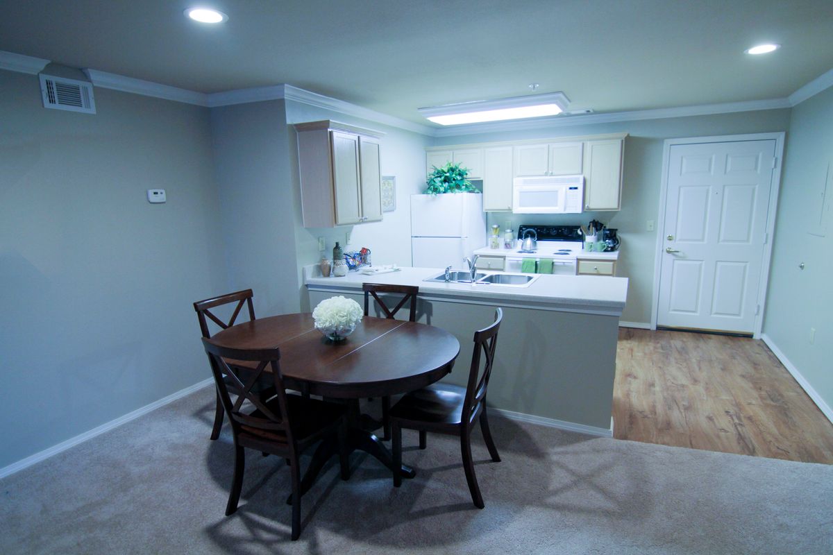 A cozy kitchen and dining area with a round table and chairs, featuring bright lighting and modern decor.