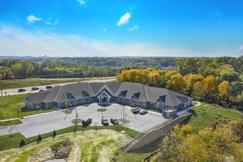 Aerial view of a residential building surrounded by trees and countryside.